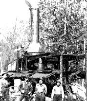 Image of some men standing in front of a steam engine donkey. This image links to a more detailed image.
