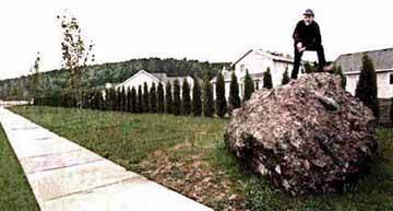 Image of a man standing on top of a large rock and a caption from the Seattle Times that reads: Mountain of Risk.