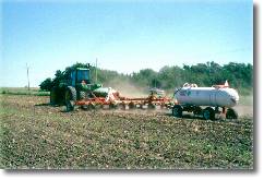 Image of liquid fertilizer being applied to a field of wheat.