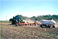 Image of liquid fertilizer being applied to a field of wheat.