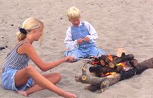 Image of two children roasting hot dogs over a fire.