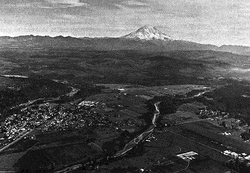Image of an aerial photograph showing the town of Orting and Mt. Rainier in the distance.  This image links to an enlargement of area shown in Orting aerial photograph.