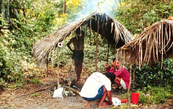 Image of some men standing under a hut.