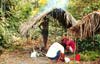 Image of some men standing under a hut.  This image links to a more detailed image.