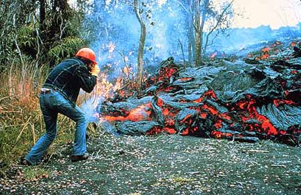 Image of a volcanologist taking a picture of a lava flow.